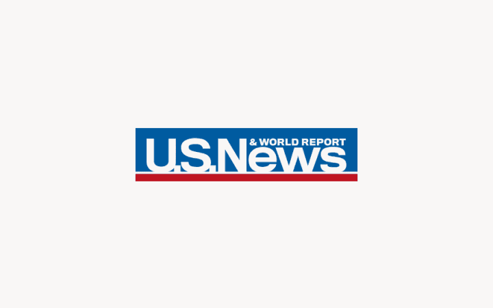 Logo U.S. News & World Report avec texte bleu sur fond rose clair, avec une ligne horizontale rouge en dessous.