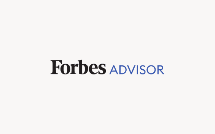 Logo Forbes Advisor avec le texte « Forbes » en noir et le texte « ADVISOR » en bleu sur fond rose clair.